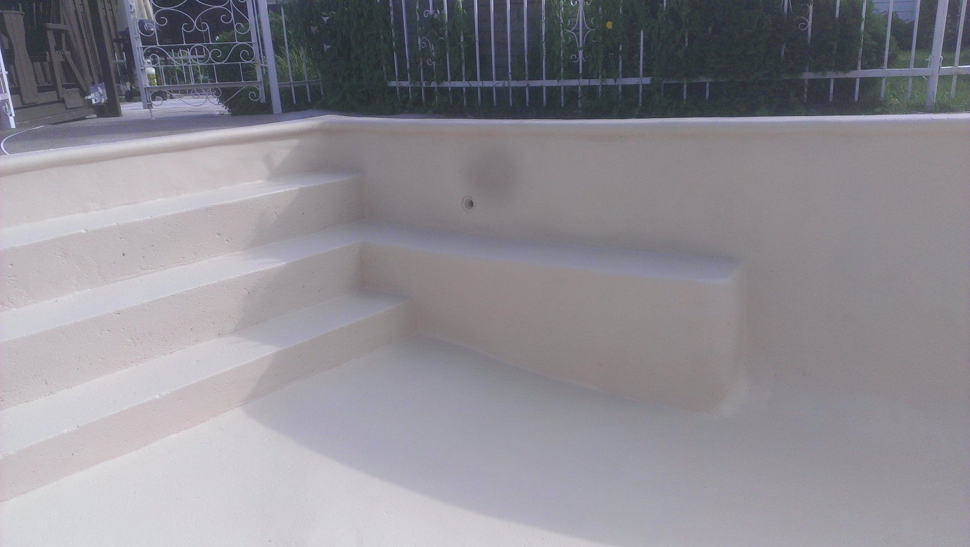 Une piscine avec des escaliers et une clôture en arrière-plan.