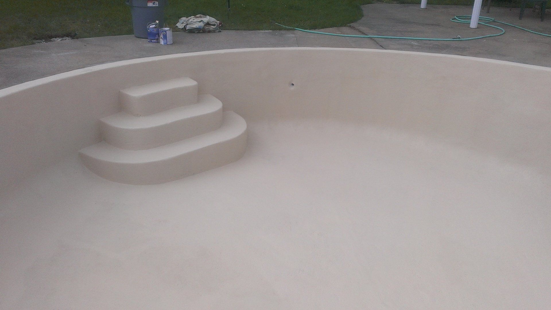 Une piscine avec des escaliers et une poubelle en arrière-plan.