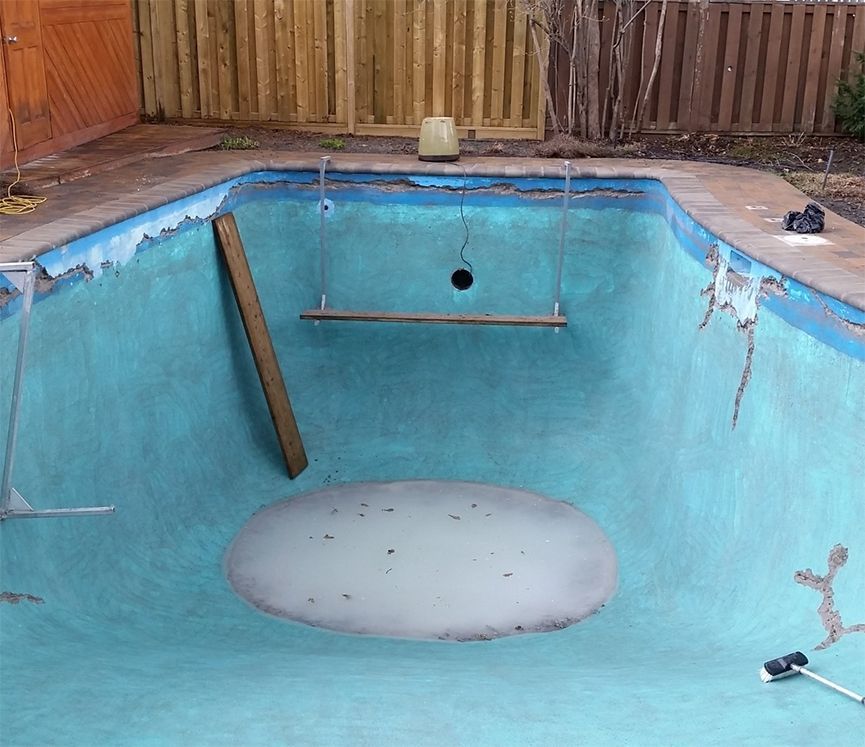 Une piscine vide avec une clôture en bois en arrière-plan