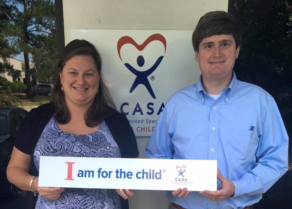 Two people holding an “I am for the child” sign in front of a CASA logo.