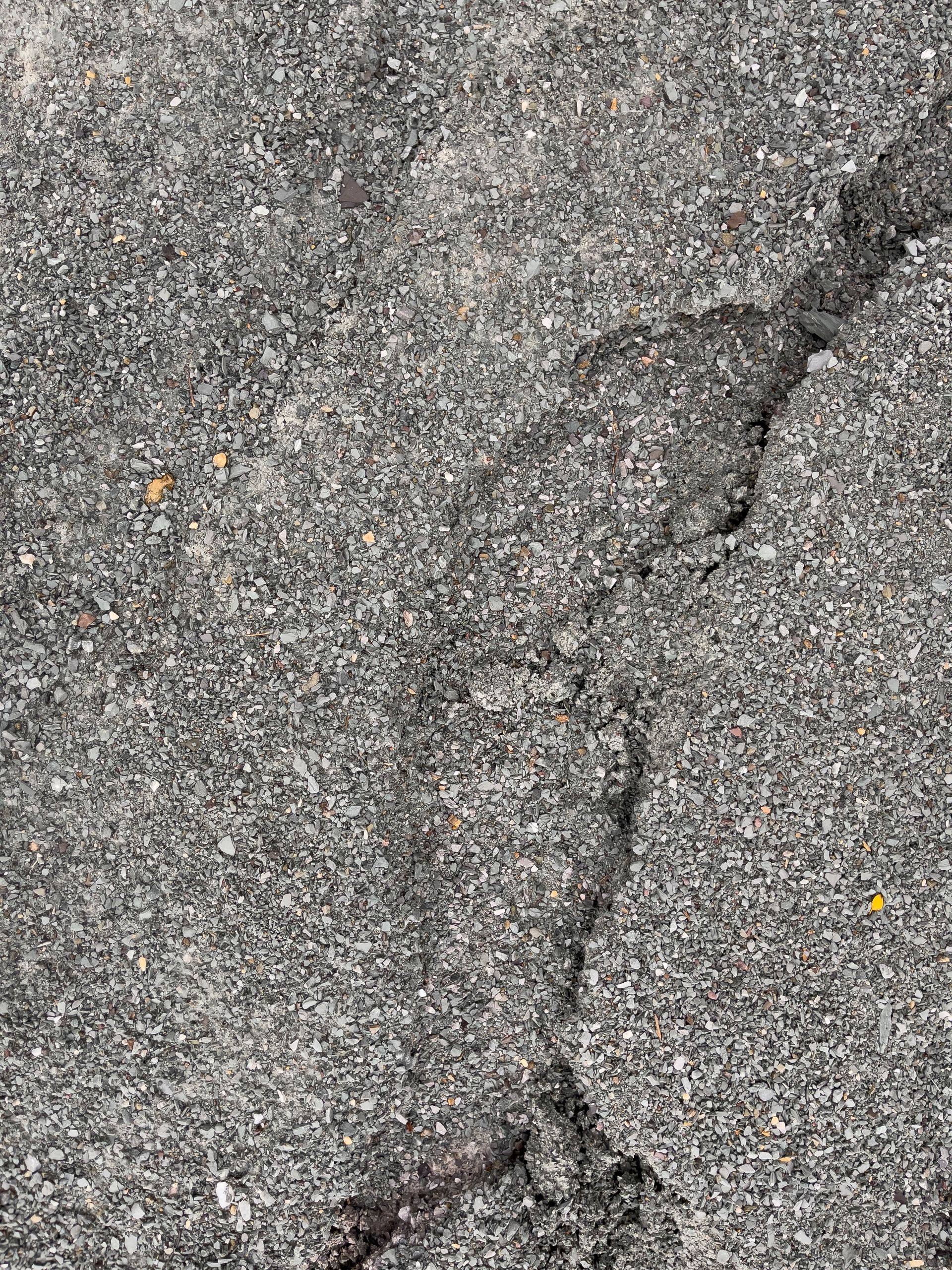 Close-up of rough gray asphalt with a long cracked line