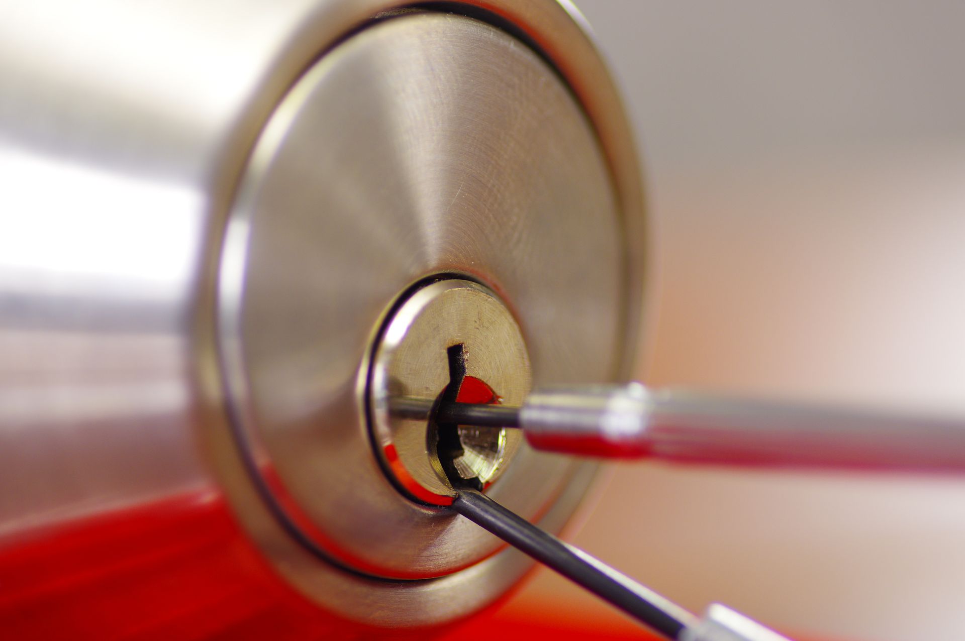 Close-up of a key being inserted into a round silver lock with a red key head Close-up of a key being inserted into a round silver lock with a red key head