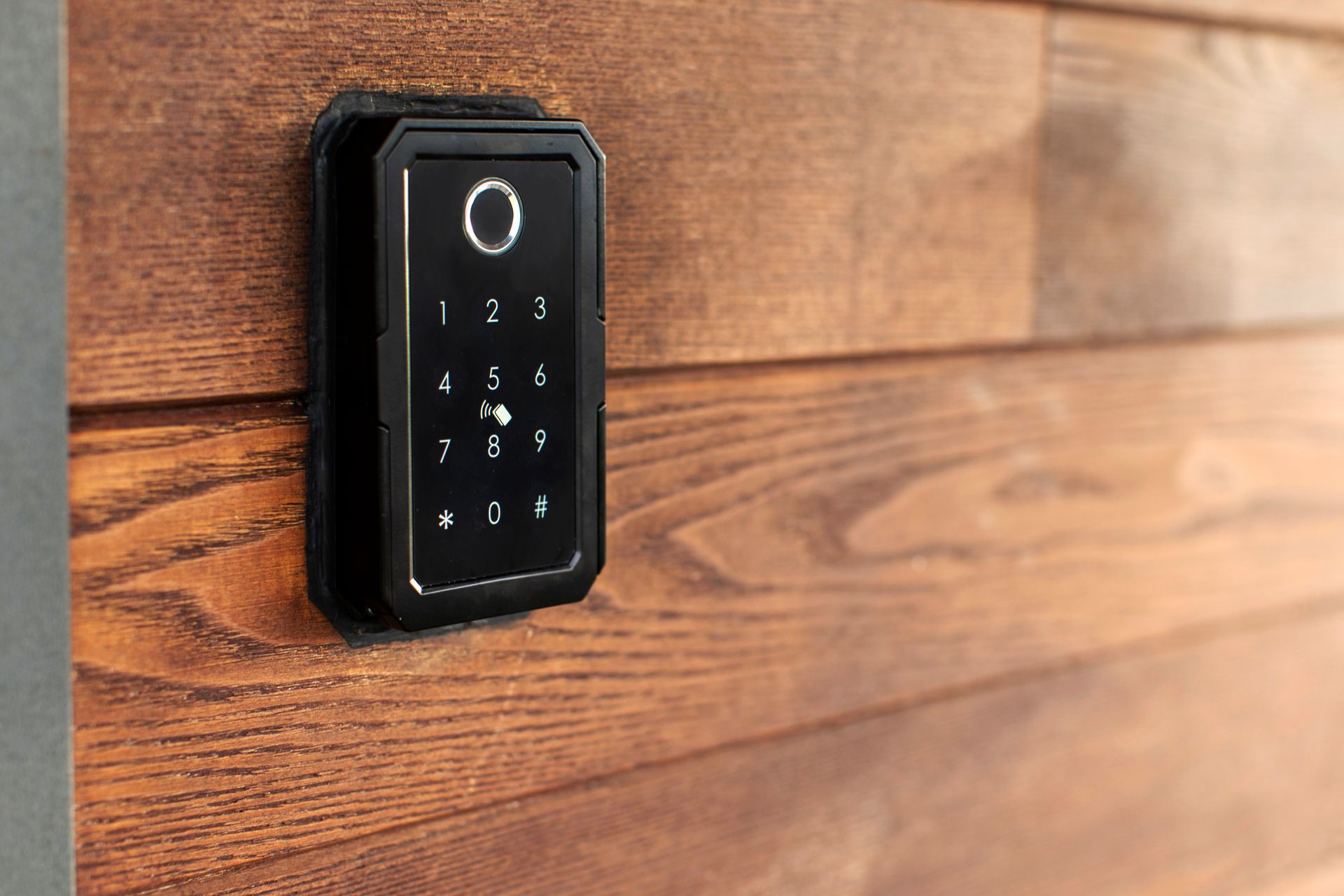 Black wall-mounted keypad lock on a wooden door Black wall-mounted keypad lock on a wooden door