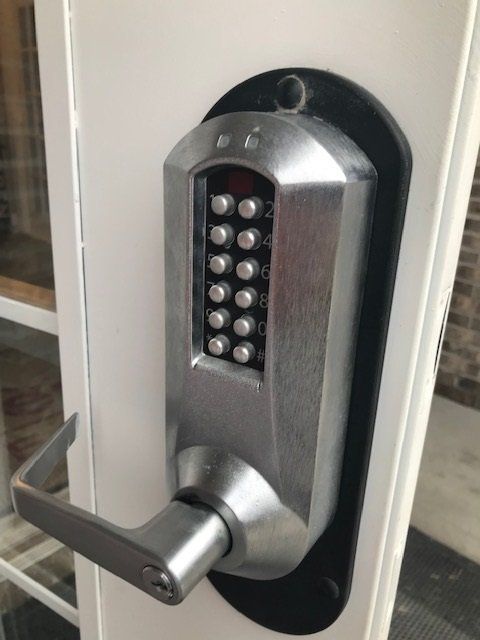 Electronic keypad door lock on a silver door handle mounted on a white door
