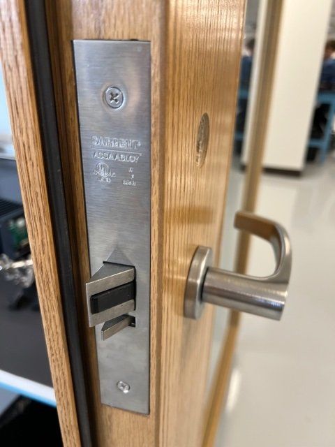 Close-up of a wood door with metal latch and silver lever handle in a hallway