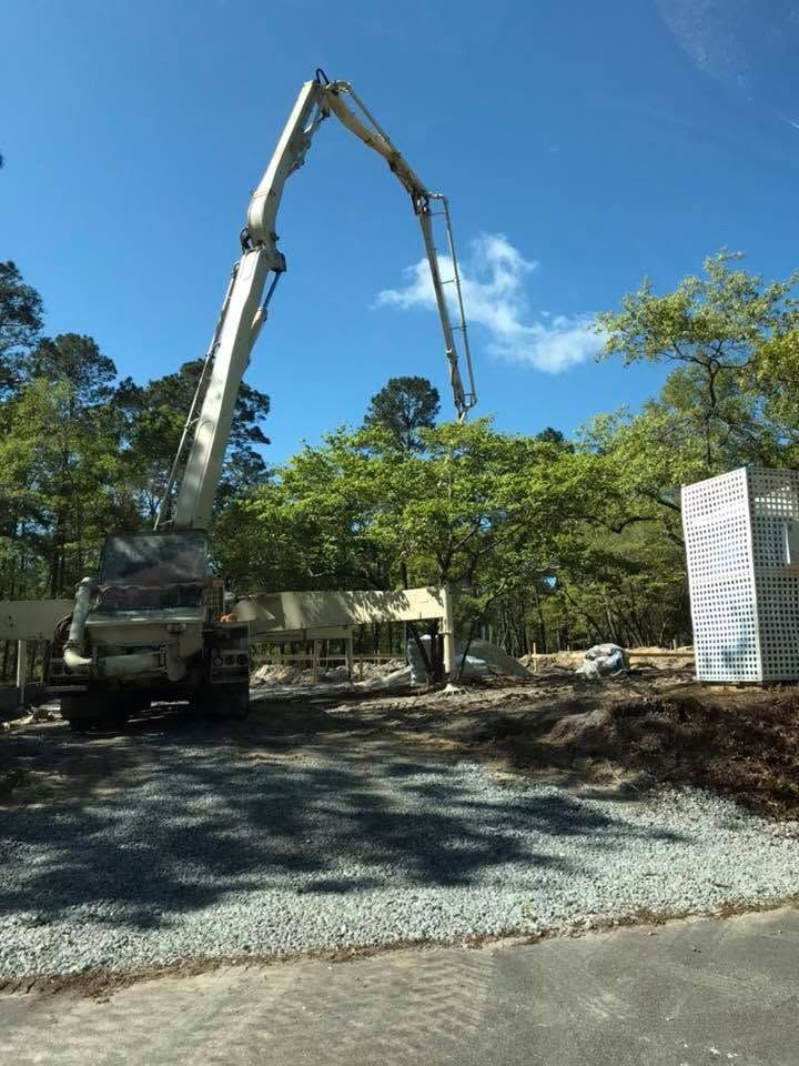 Concrete pump truck pouring on a gravel construction site under a blue sky