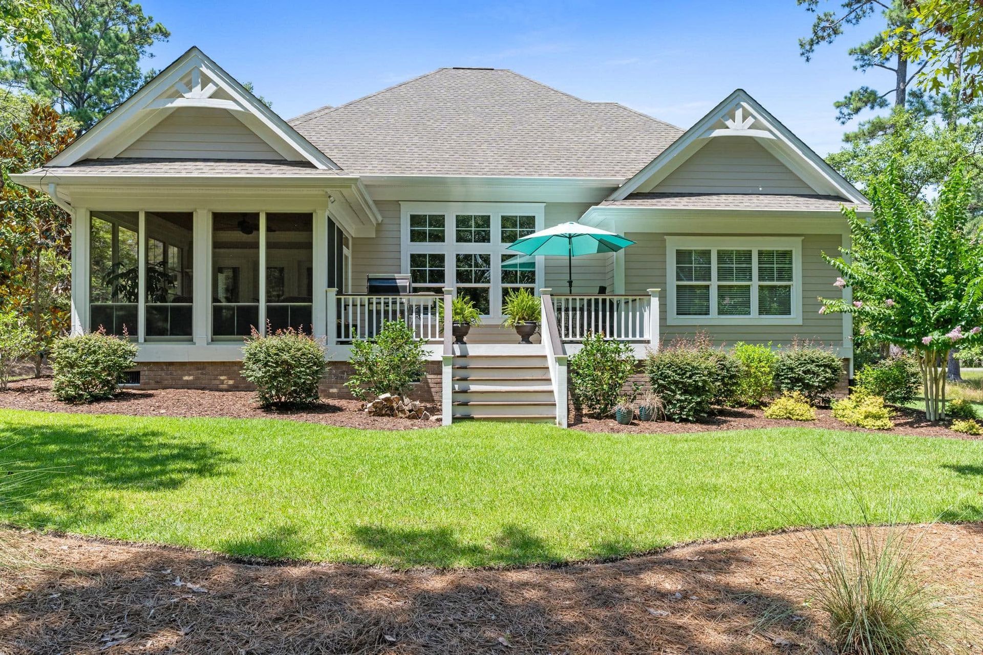 Single-story white house with a covered porch, front steps, and a green lawn under a sunny sky