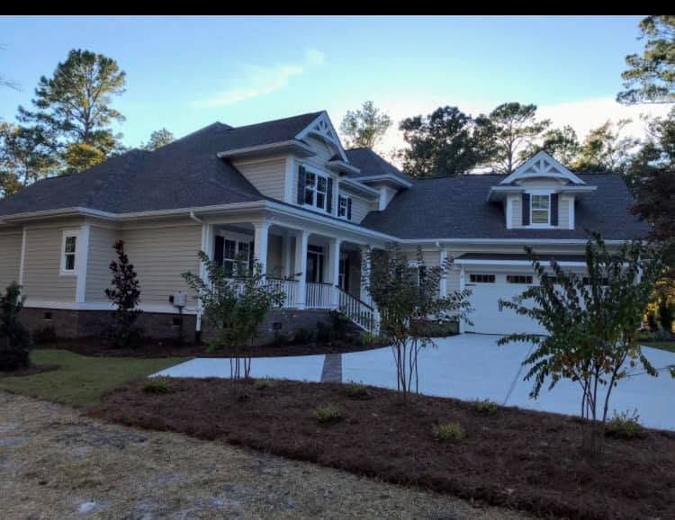 Suburban house with gray roof, white garage, and front porch at dusk