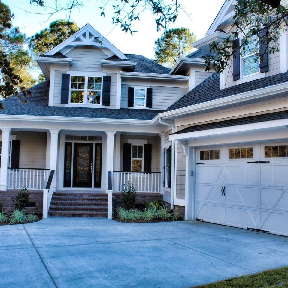 Two-story gray house with white trim, front porch, and attached garage at dusk