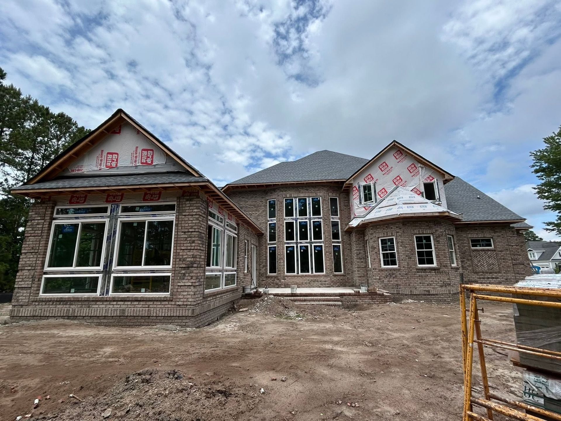 New house under construction with unfinished stone exterior and cloudy sky above