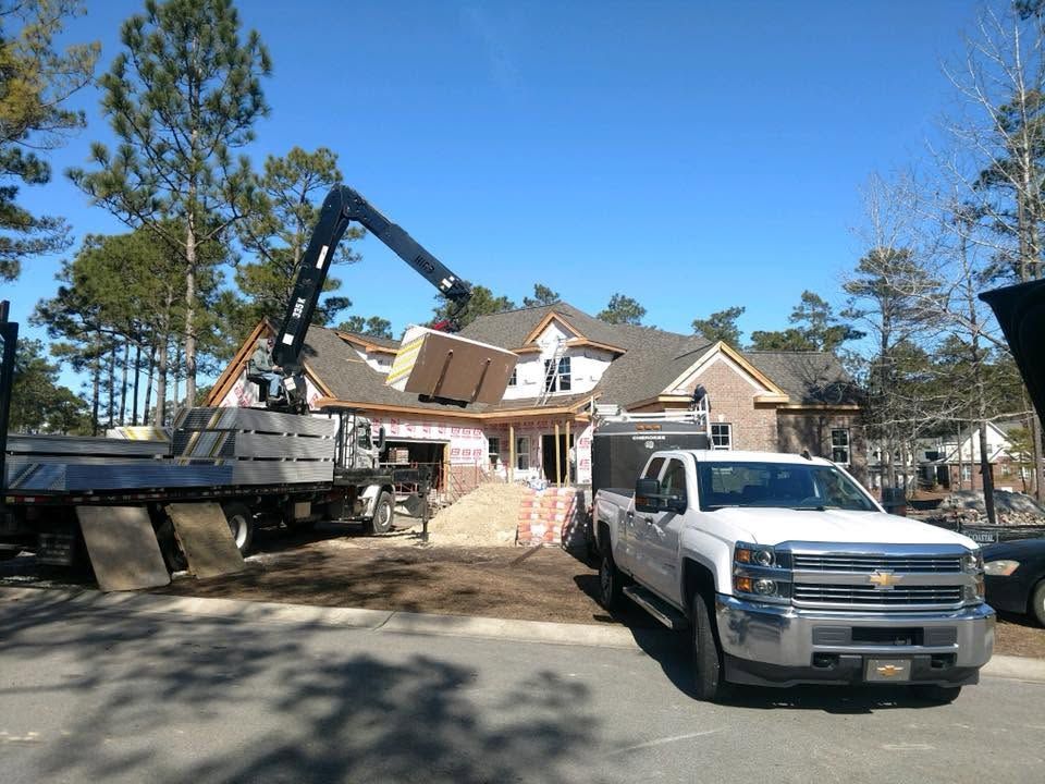 Construction equipment and a white pickup truck beside a house under renovation outdoors