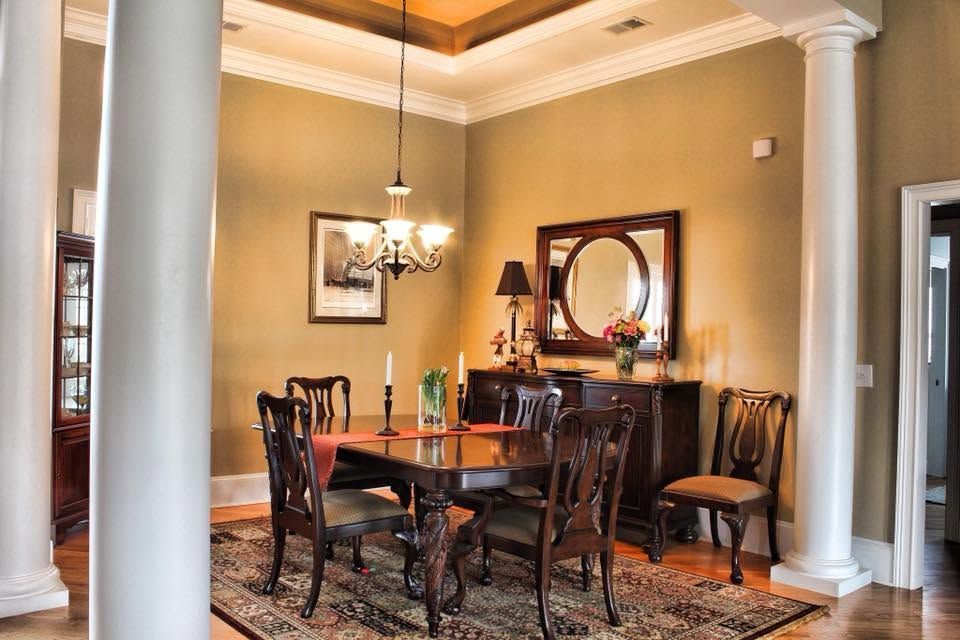 Elegant dining room with dark wood table, chandelier, large mirror, and white columns