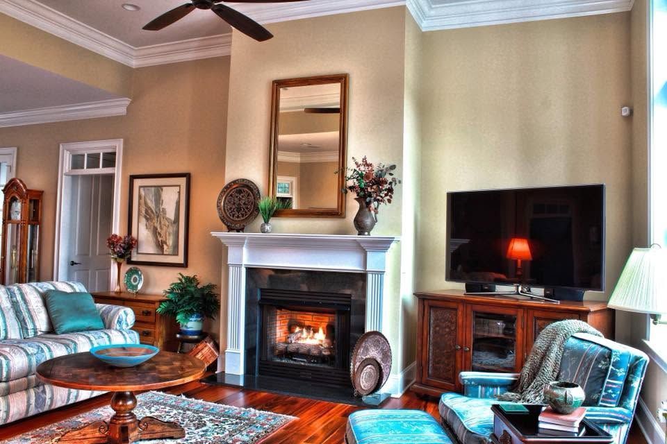 Cozy living room with fireplace, TV, turquoise chairs, patterned sofa, and warm beige walls