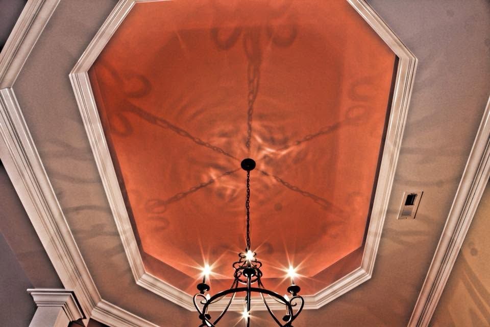 Octagonal orange ceiling medallion with a black chandelier hanging below in a formal room