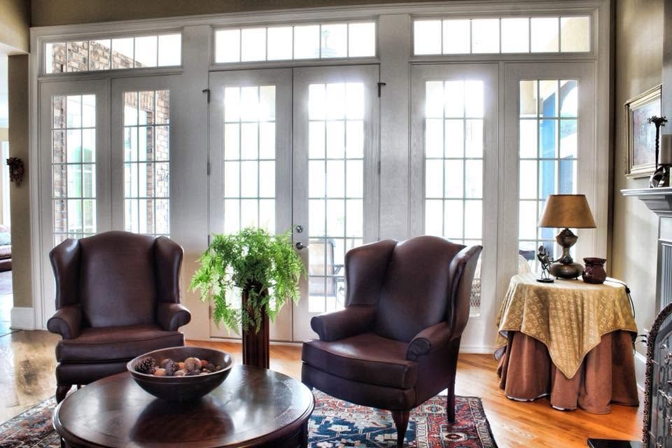 Bright living room with two dark armchairs, a round coffee table, and large French doors letting in daylight