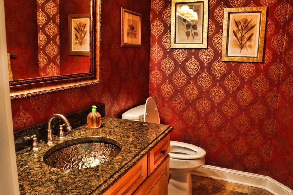 Elegant red-tiled bathroom with a stone sink, mirror, and framed wall art.