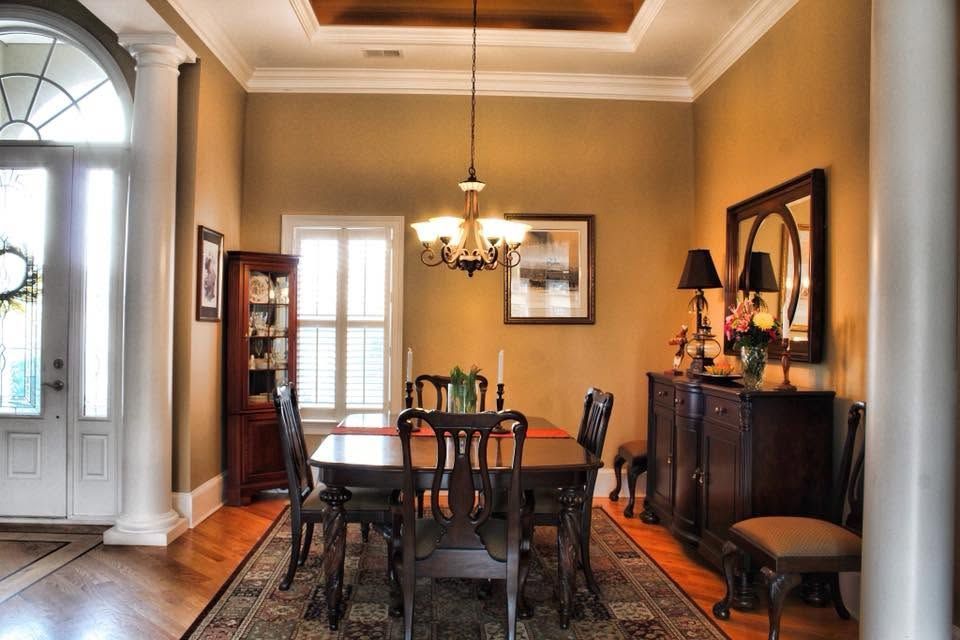 Formal dining room with wooden table, chandelier, arched doorway, and warm beige walls