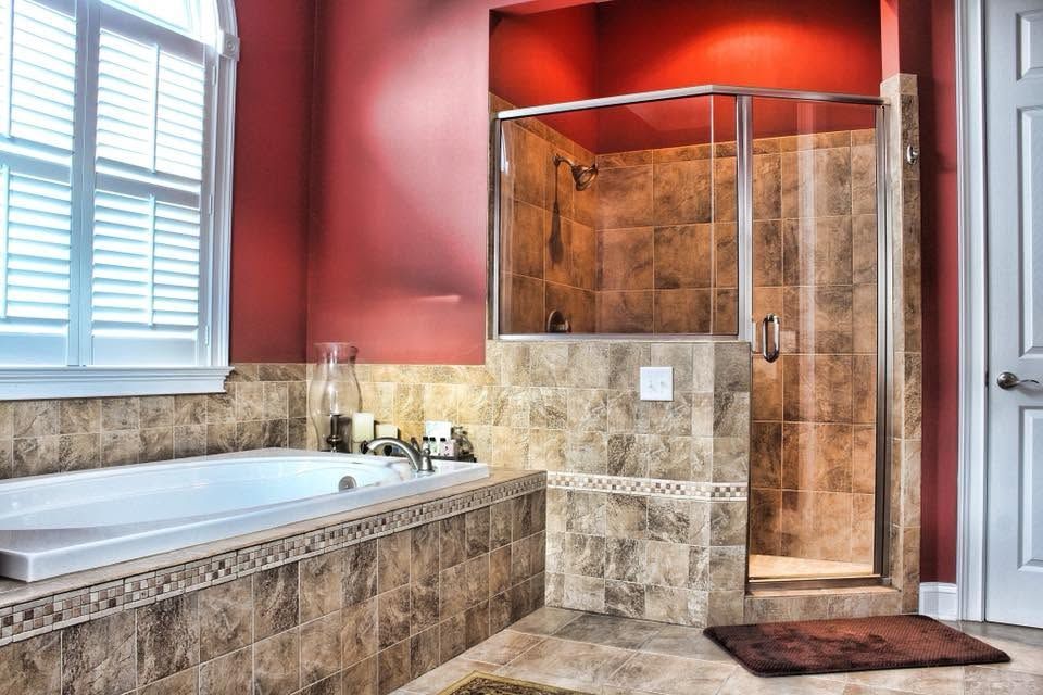 Luxury bathroom with red walls, tiled soaking tub, and glass-enclosed shower.