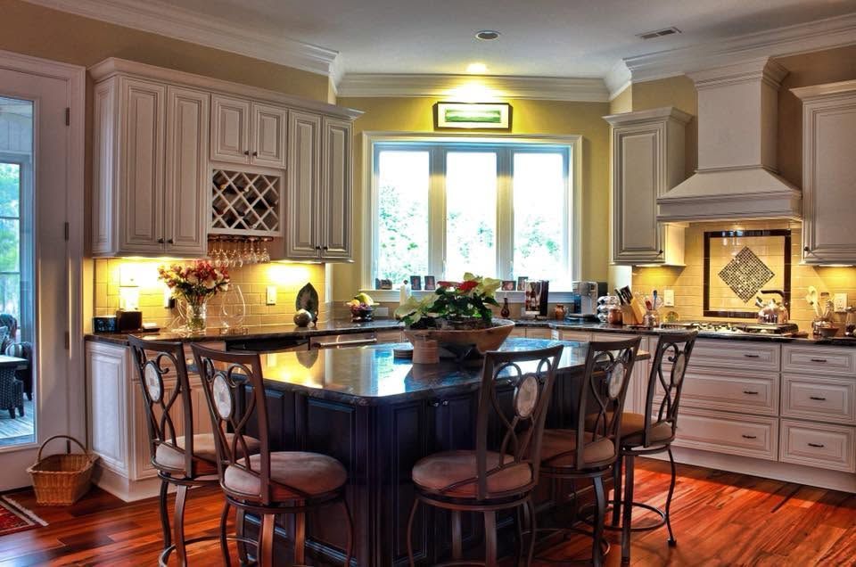 Spacious cream kitchen with central island, pendant lights, and sunlit window over hardwood floors