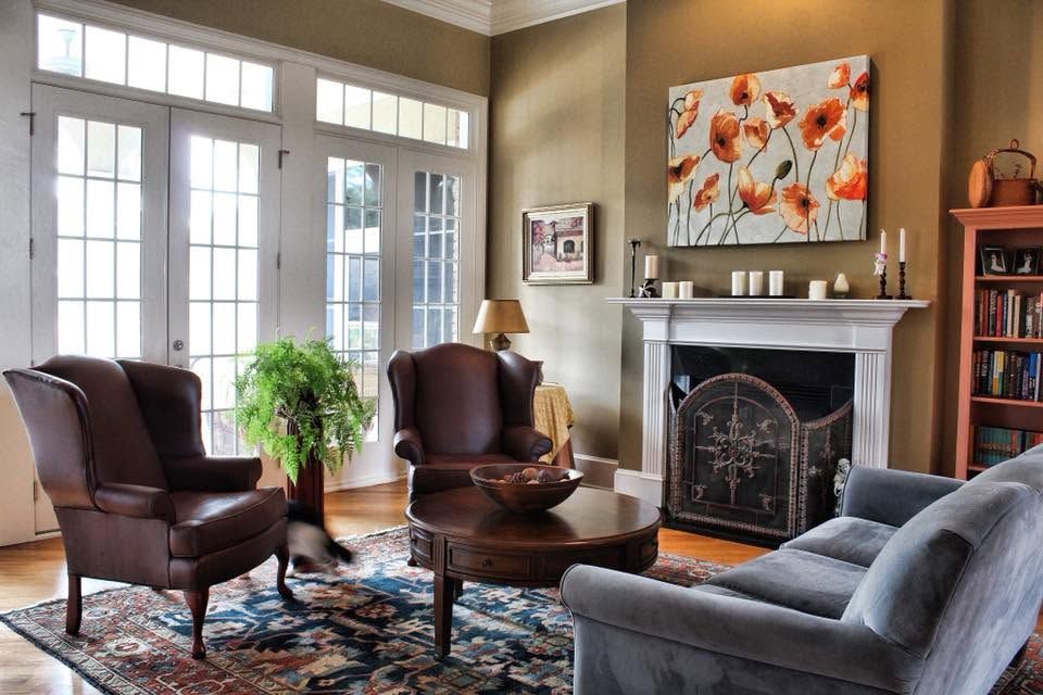 Cozy living room with leather chairs, gray sofa, fireplace, and large floral painting