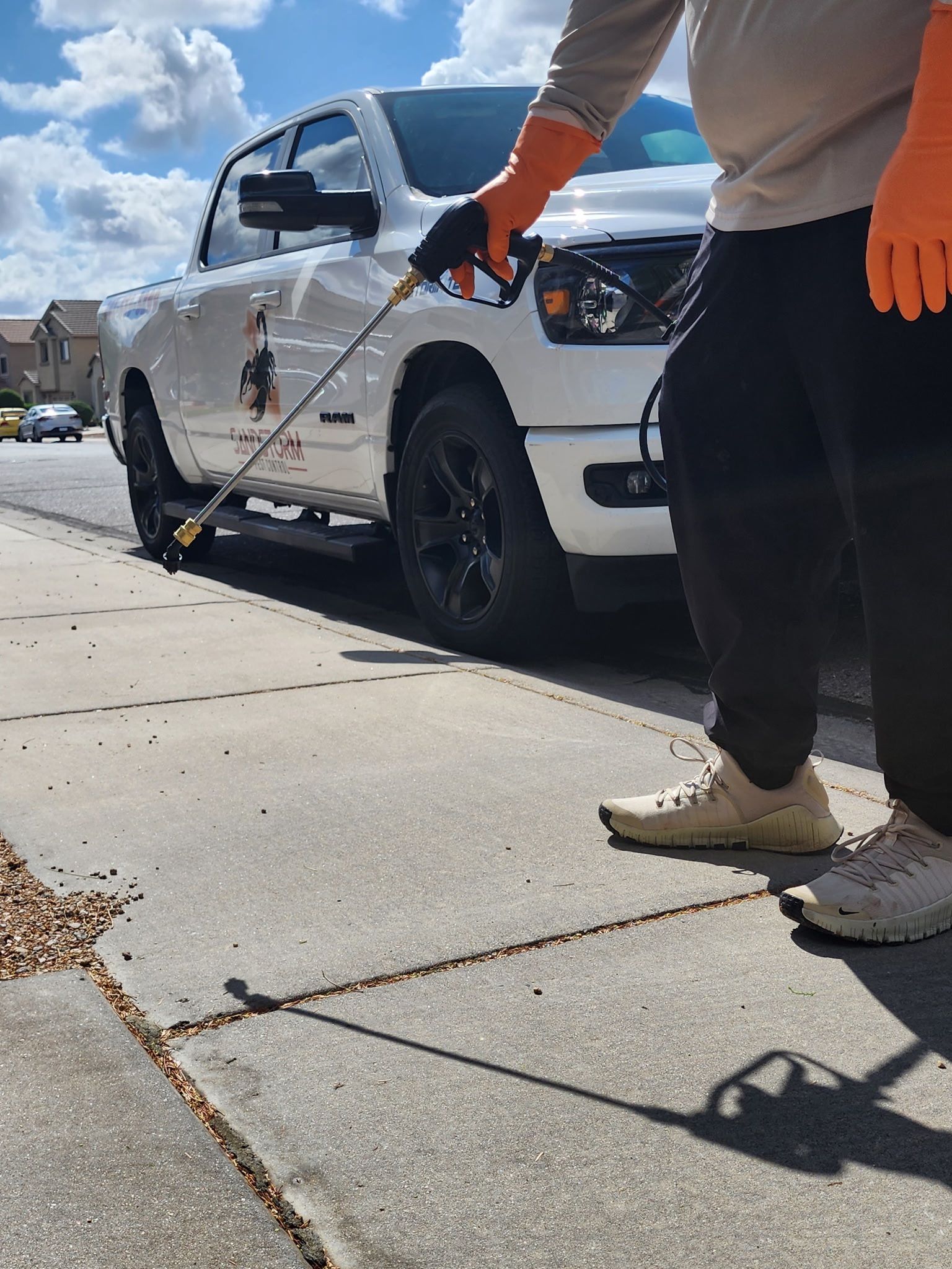 Person pressure-washing a white pickup truck on a sunny driveway