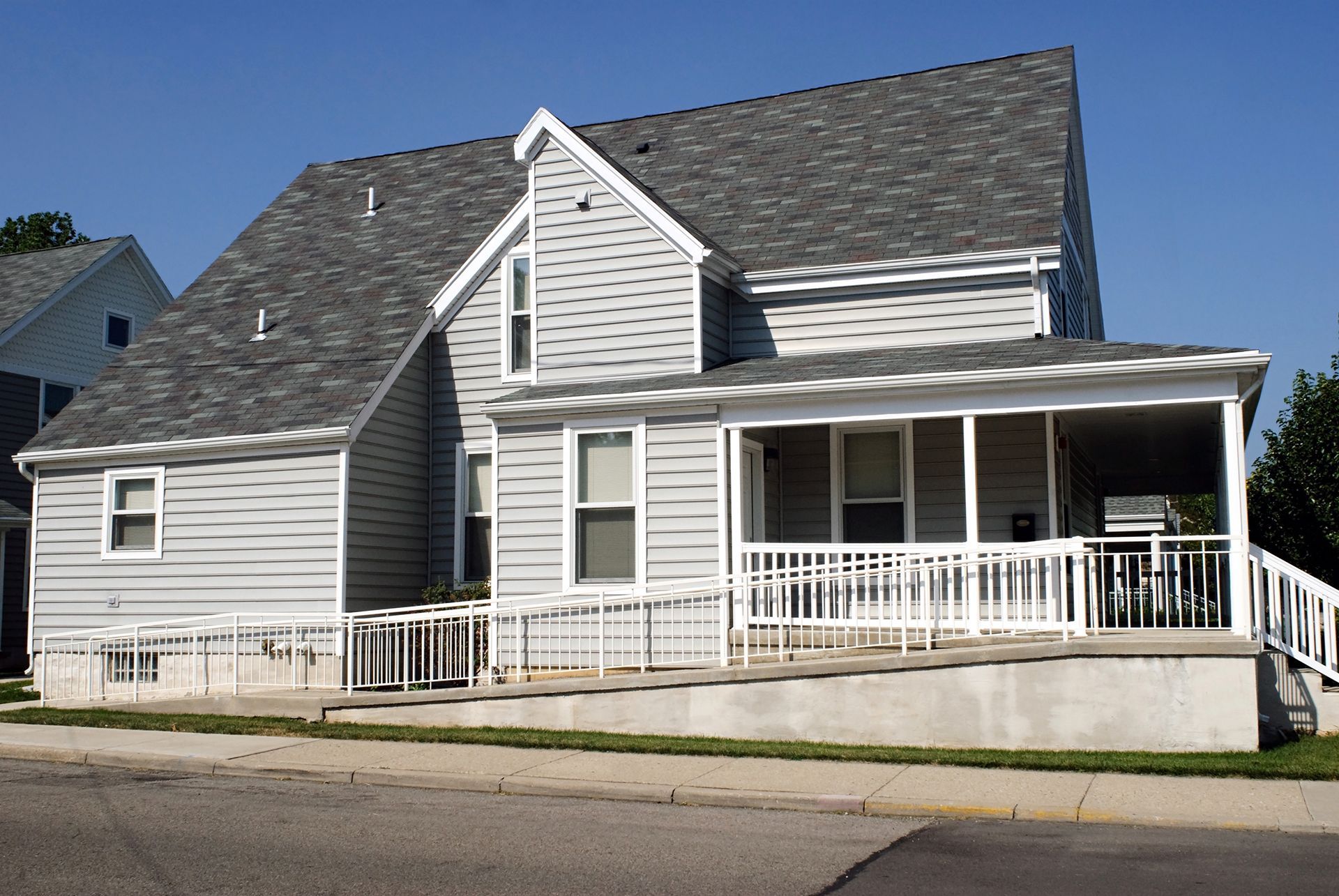 A white house with a gray roof and a white porch