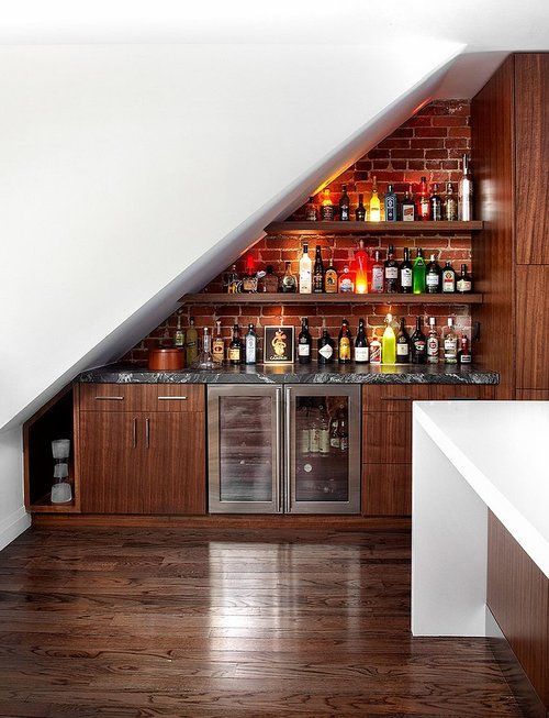 A kitchen with a bar underneath the stairs