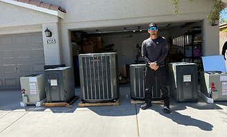 Person standing in front of open garage with large HVAC units and bins on a driveway