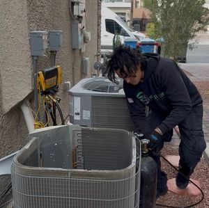 Technician working on an outdoor air conditioning unit beside a house