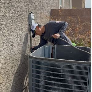 Technician inspecting an outdoor HVAC unit beside a stucco wall