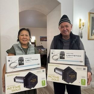 Two people holding Lightstick and Active Gold product boxes indoors