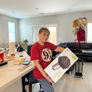 Smiling person in red shirt holding an Active Sound box in a bright kitchen