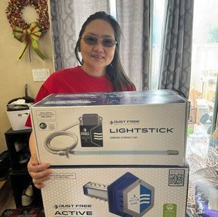 Woman indoors holding two boxed products, including a Lightstick box and a blue device box.