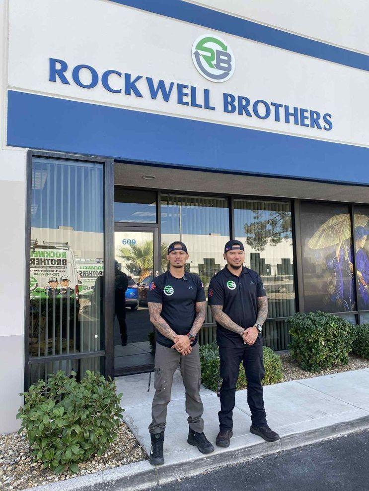 Two uniformed employees stand outside the Rockwell Brothers storefront.