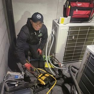 Technician servicing HVAC unit with tools in a cramped indoor space