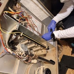 Technician in blue gloves repairing the exposed interior of a metal appliance with wires and components visible