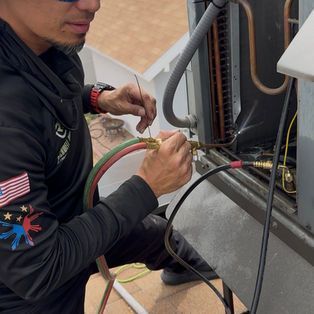 Technician connecting colored cables to an outdoor electrical panel while kneeling on the floor
