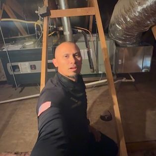Person taking a selfie in a dim basement with HVAC ducts and furnace equipment in the background