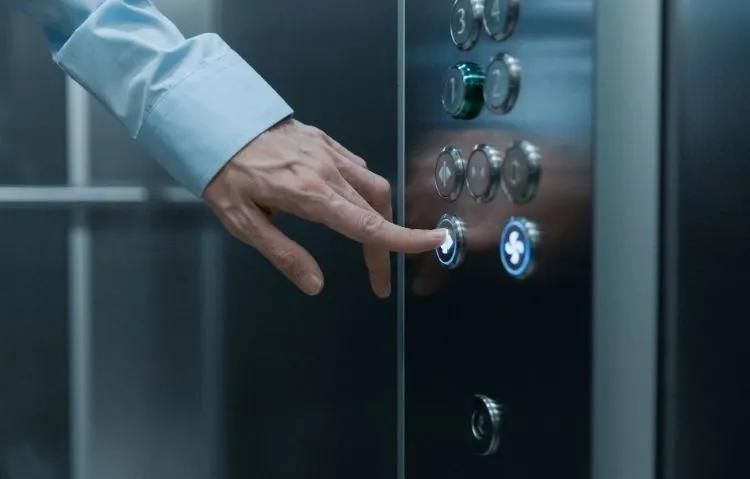 Hand pointing at illuminated elevator buttons with floor numbers and directional arrows