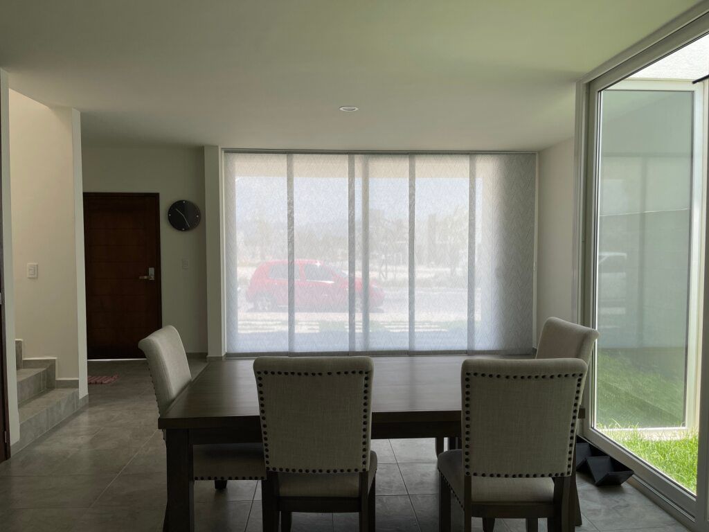 A Dining Room With a Table and Chairs and a Large Window — Tully Blinds in Mission Beach, QLD