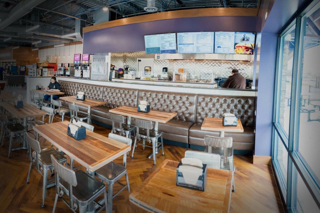 Restaurant interior with tables, a counter, and a cook. The walls are purple.