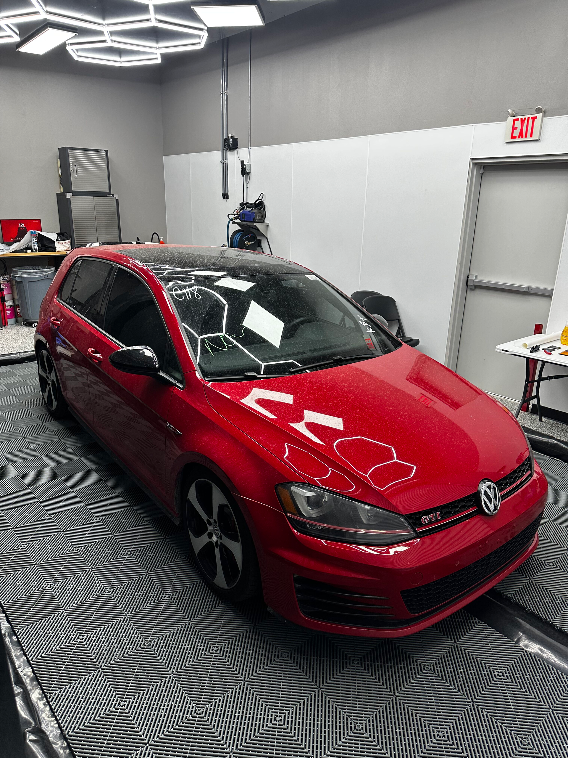 Red Volkswagen Golf GTI parked inside a garage. The car is shiny, with a black roof and wheels.