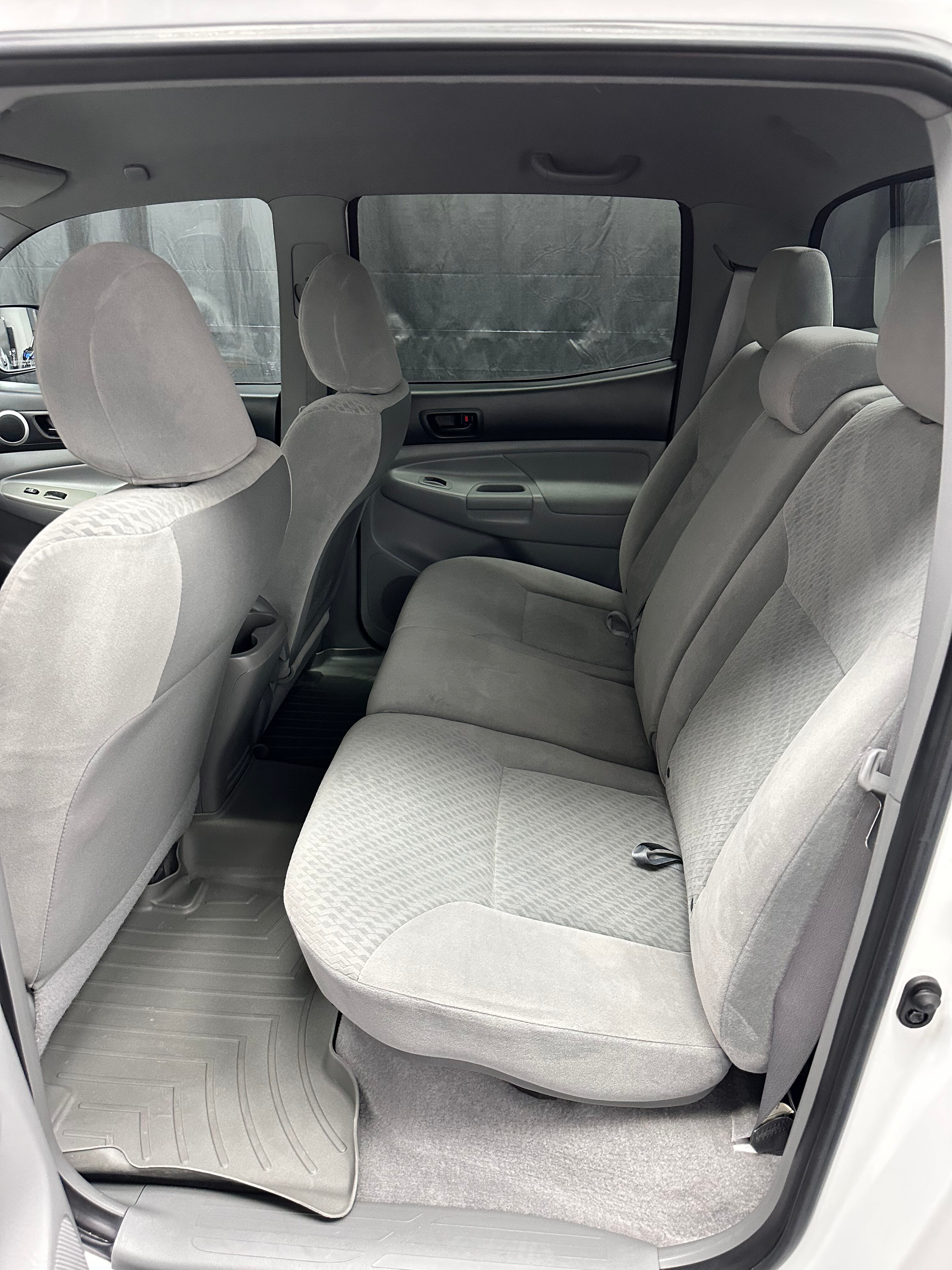 Interior view of a white pickup truck with grey cloth seats. The back seats are visible, with headrests.