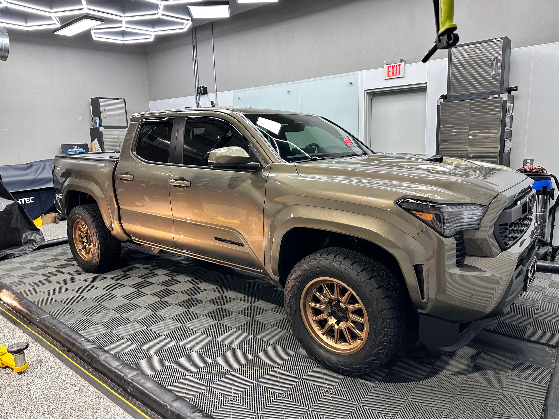 Brown Toyota Tacoma truck parked inside a garage, showcasing detailing work.