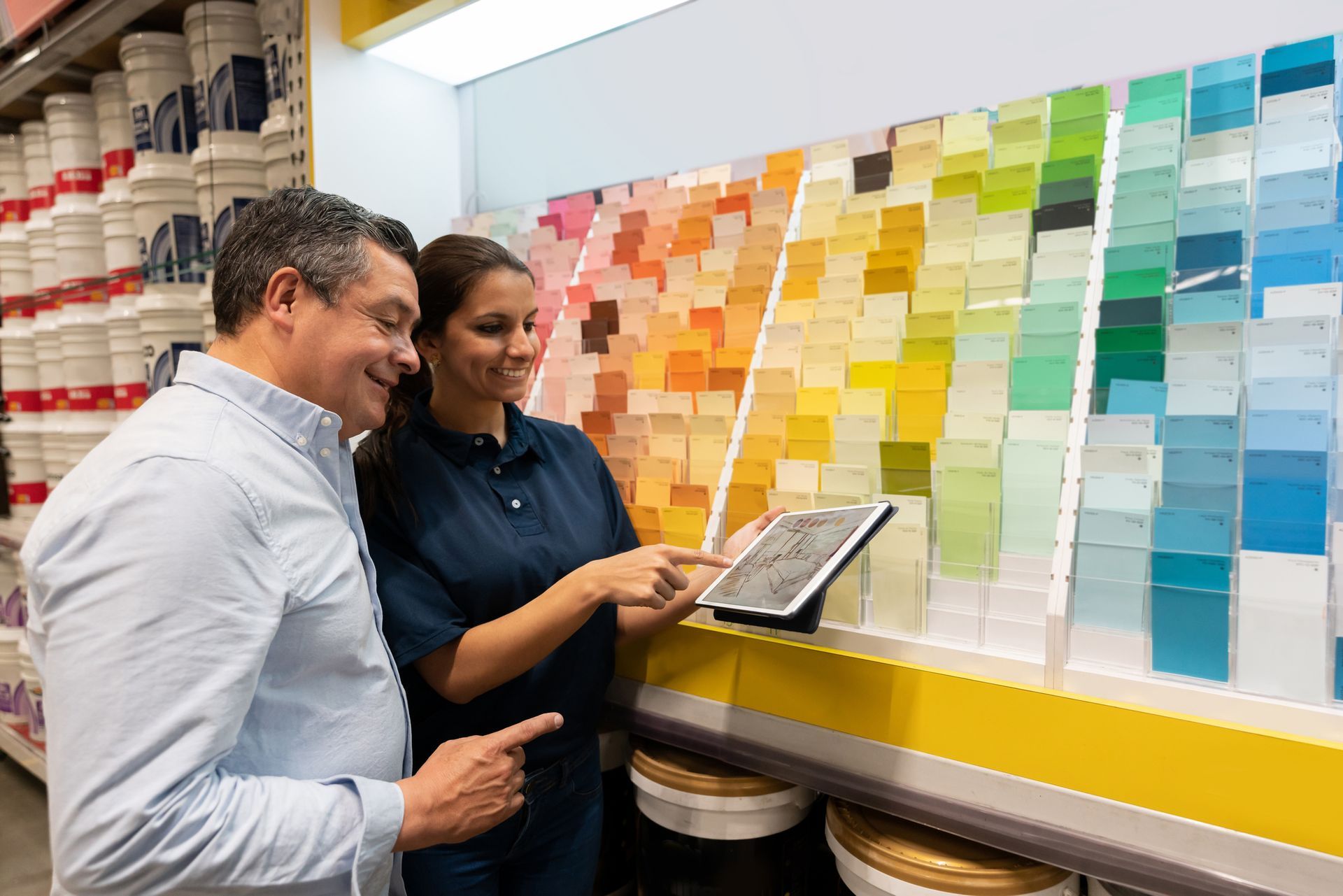 Man at hardware store looking at Benjamin Moore paint colors and talking to the saleswoman