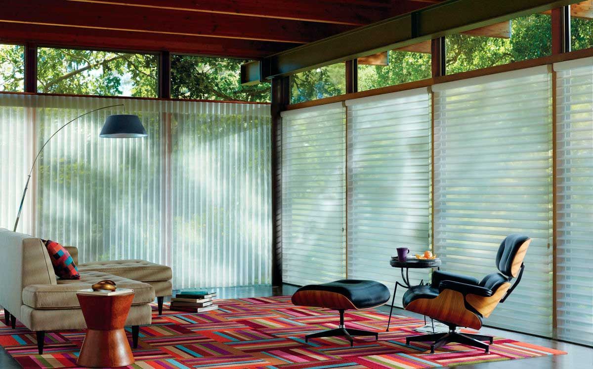 A living room with a couch , chair , ottoman and rug.