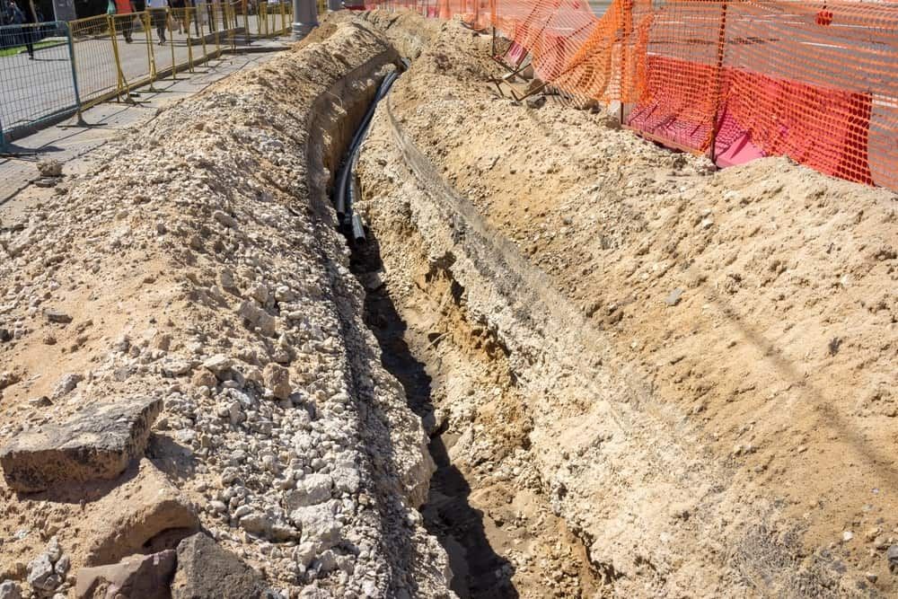 A Trench is Being Dug in the Dirt Next to a Fence — Wards Group QLD in Blackbutt, QLD