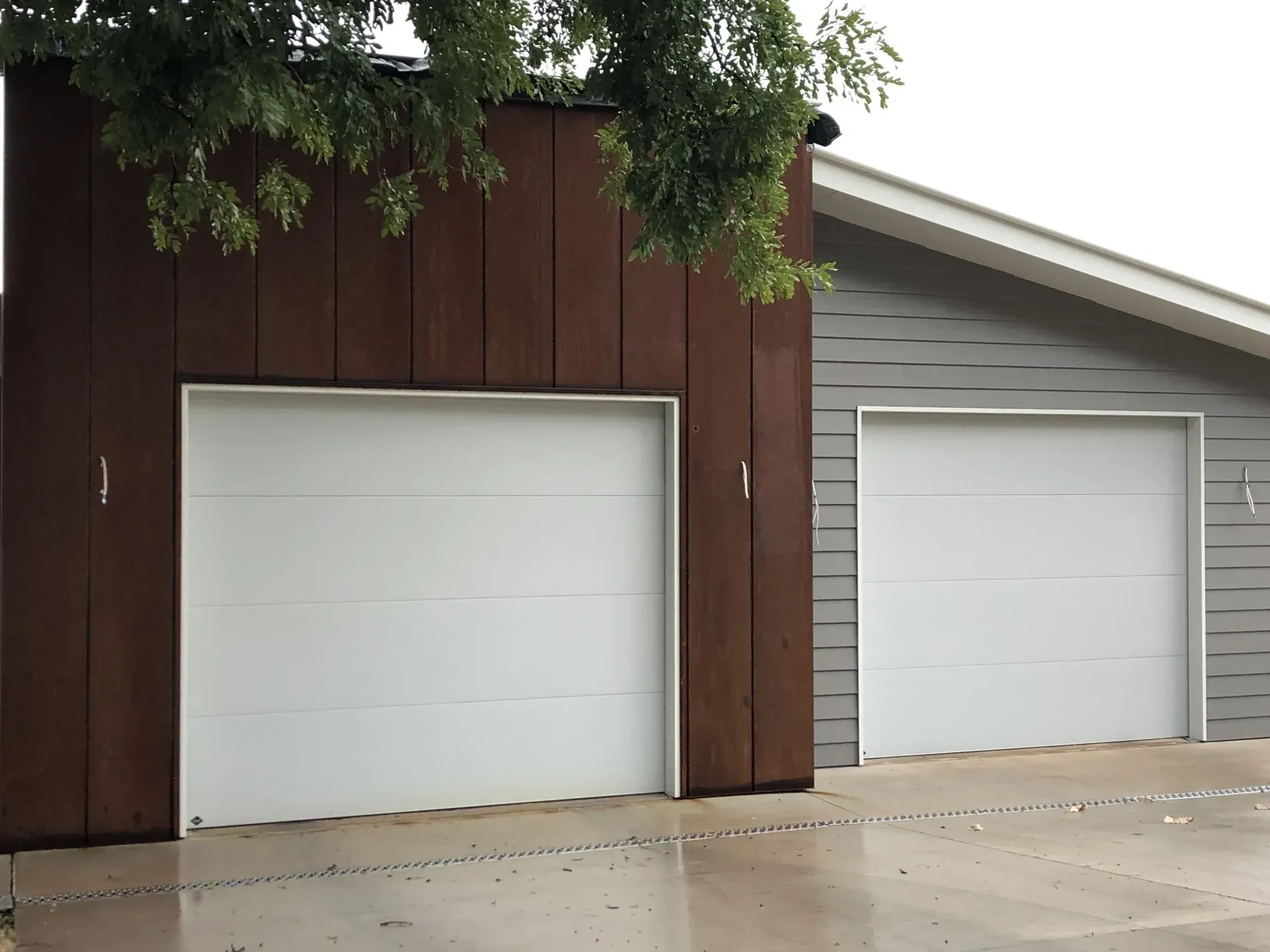 Two garage doors, one brown and one gray, in an outdoor setting. — Wards Group QLD In Kingaroy, QLD