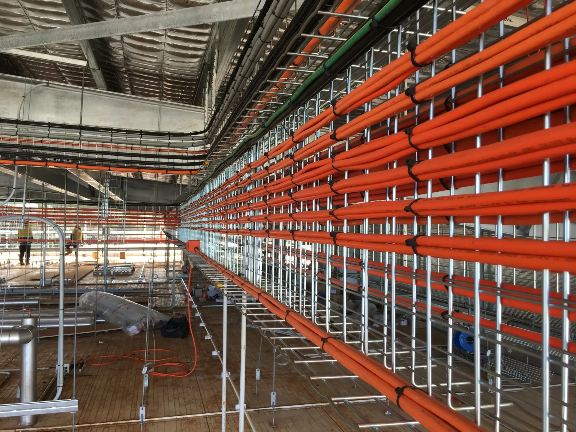 Orange cables bundled and secured along metal scaffolding in a construction site. — Wards Group QLD In Kingaroy, QLD