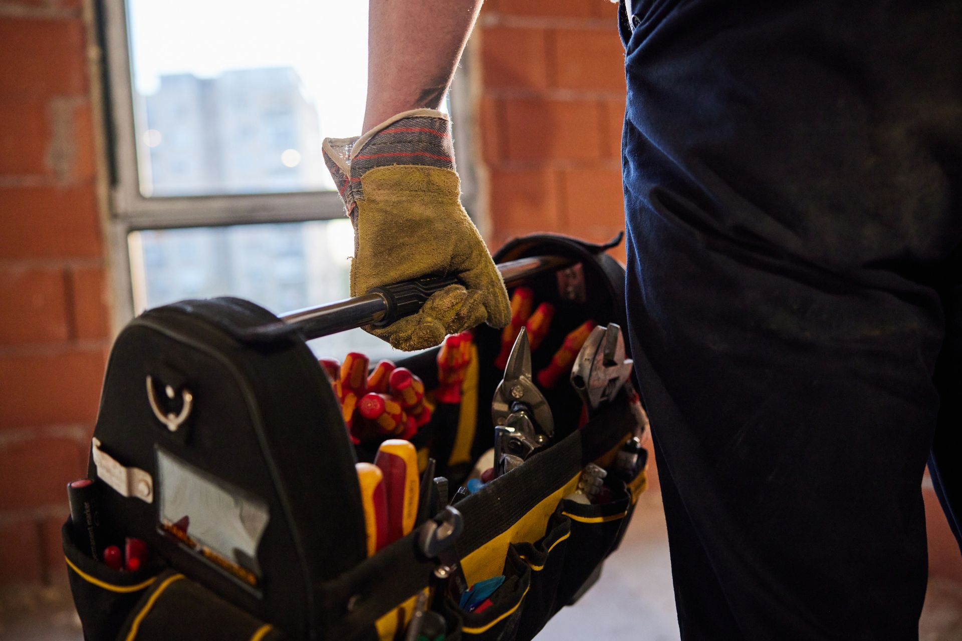 A man is carrying a tool bag filled with tools.